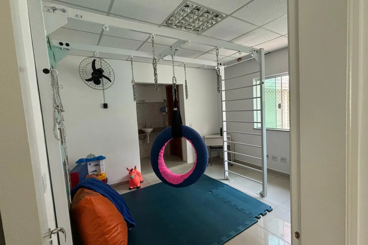 Sala de integração sensorial com balanço suspenso e tatame